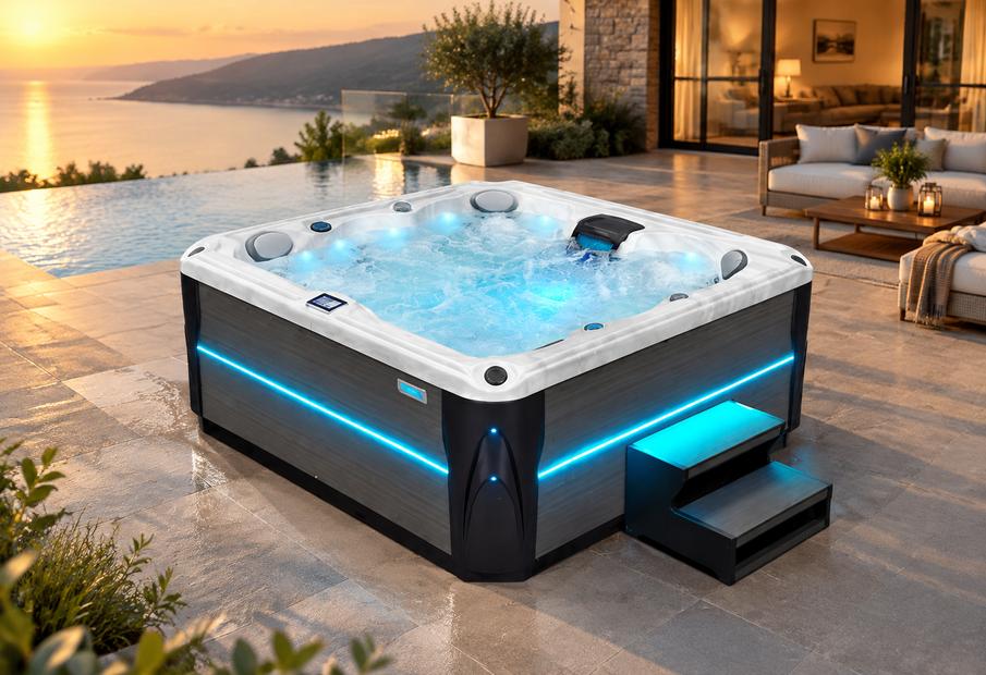 A high-angle shot of a hot tub with blue LED lighting on a stone patio at night