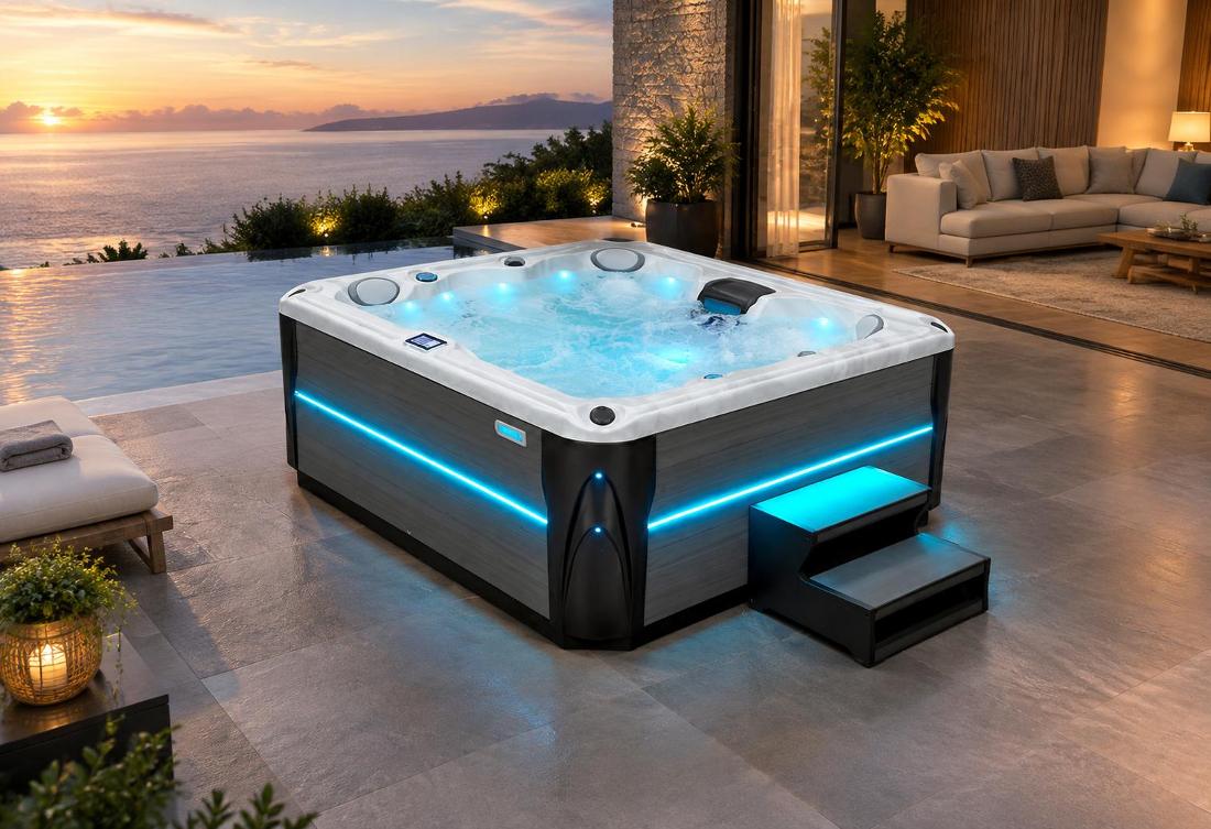 A high-angle shot of a hot tub illuminated by blue interior LED lighting on a stone patio at night