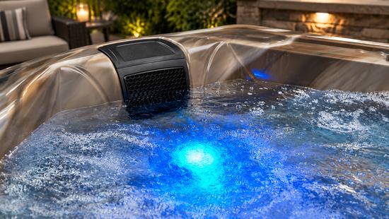 A conceptual detail shot focusing on the blue LED lighting feature at the bottom of the tub, casting a soft glow through the water.