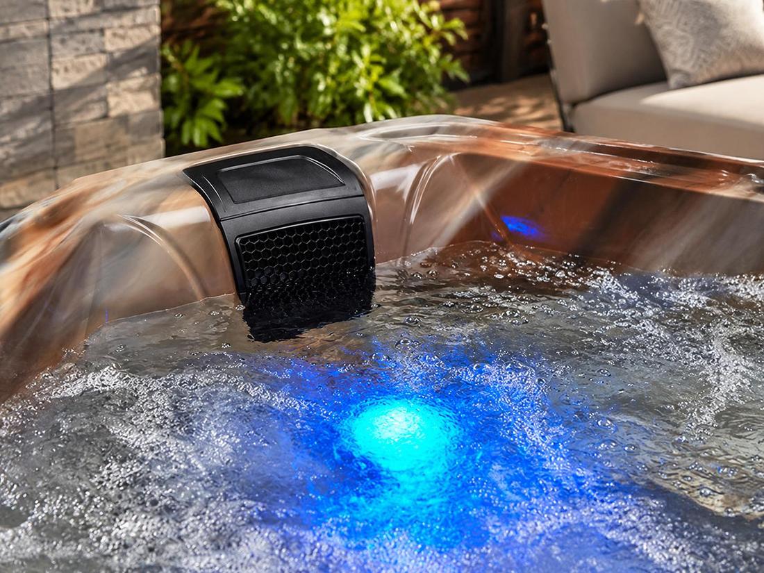 A conceptual detail shot focusing on the blue LED lighting feature at the bottom of the tub, casting a soft glow through the water.